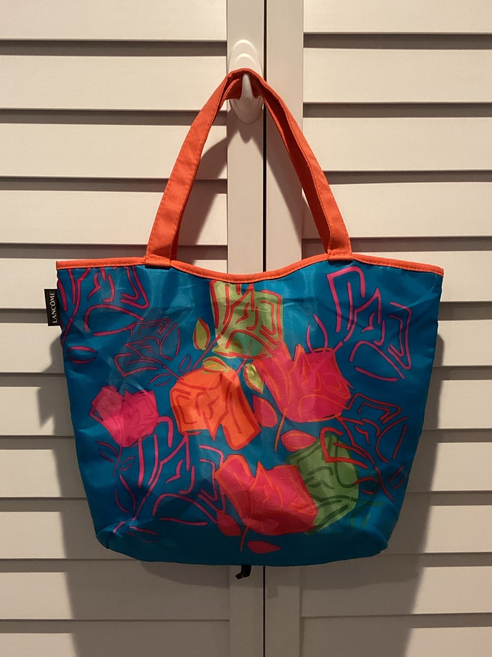 Lancome Reversible Blue Floral Tote with Orange Handles and solid Pink.